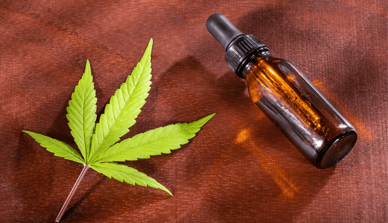 Braune Flasche mit Hanföl und Hanfblatt auf Holzuntergrund